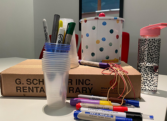 items that could be used for the composition. Cardboard box, drink bottle, elastic bands, pens, plastic cups and a biscuit tin