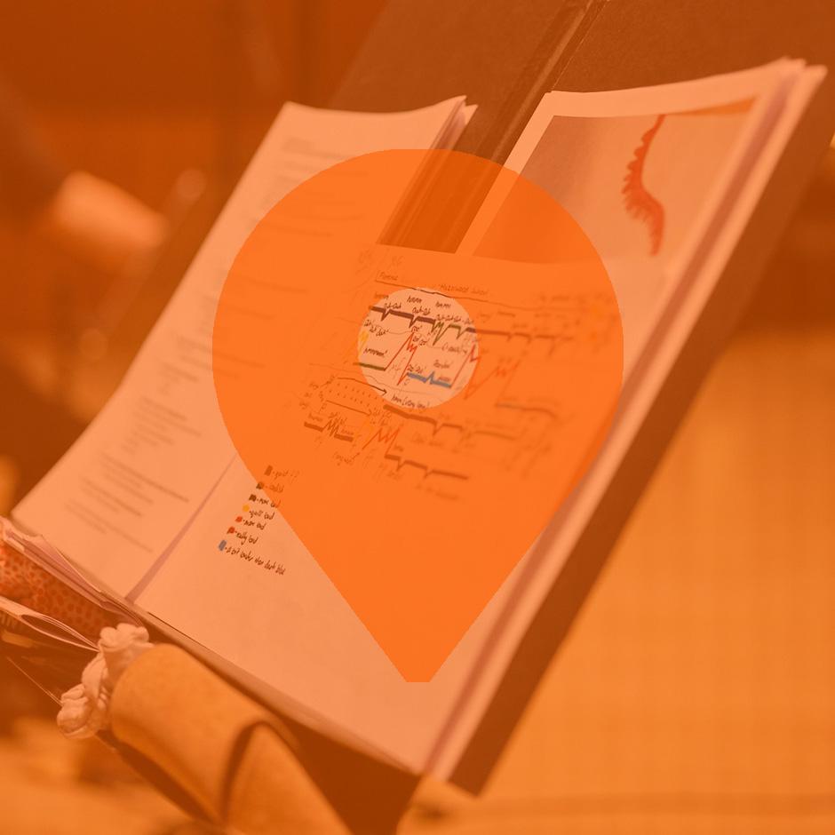 A graphic score placed on a music stand, with an orange pindrop overlayed on top