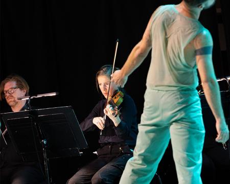 dancer in the foreground with violinist in the background