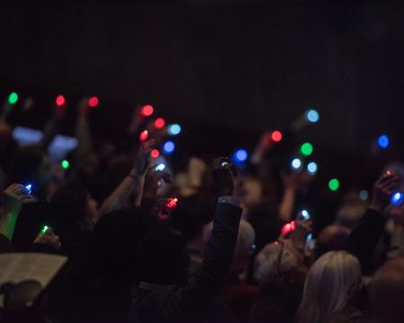 Audience members holding fingerlights in the air