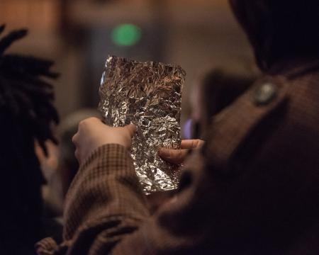 A close-up shot of an audience member holding a piece of foil