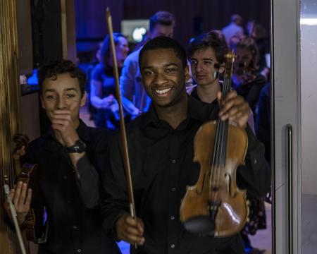 An image of two school pupils holding a violin at the London Sinfonietta Sound Out concert