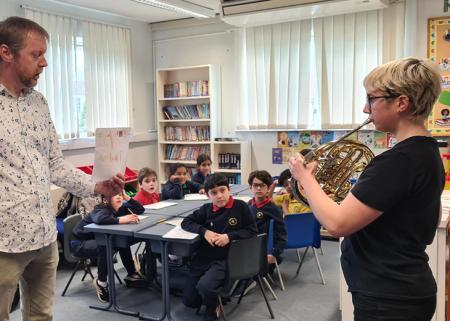 An image of school children and a french horn player at a London Sinfonietta composition workshop in Hadley Wood Primary School